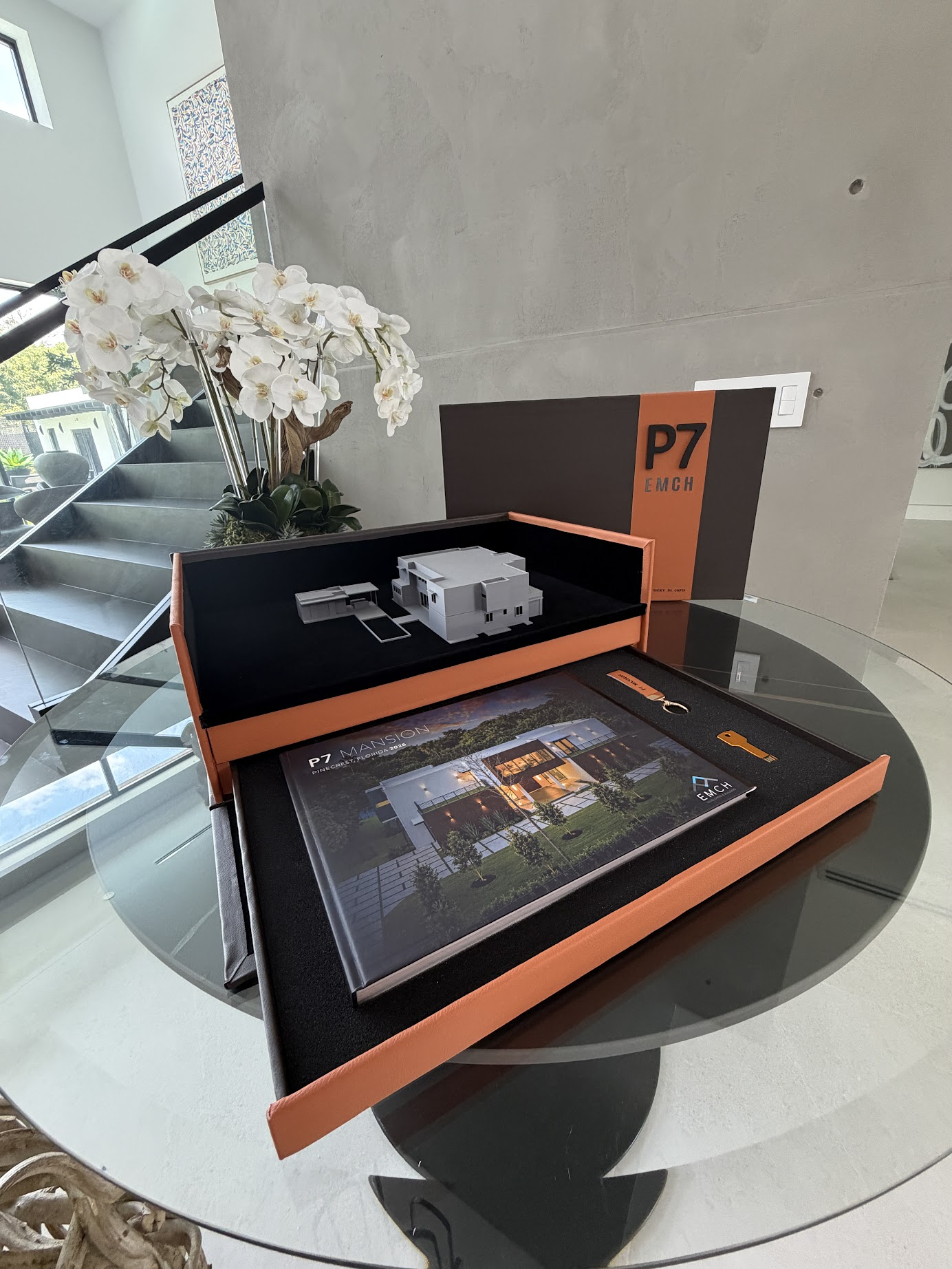 The Casa Completa presentation case open — the home's 3D scale model, the project book and its presentation key